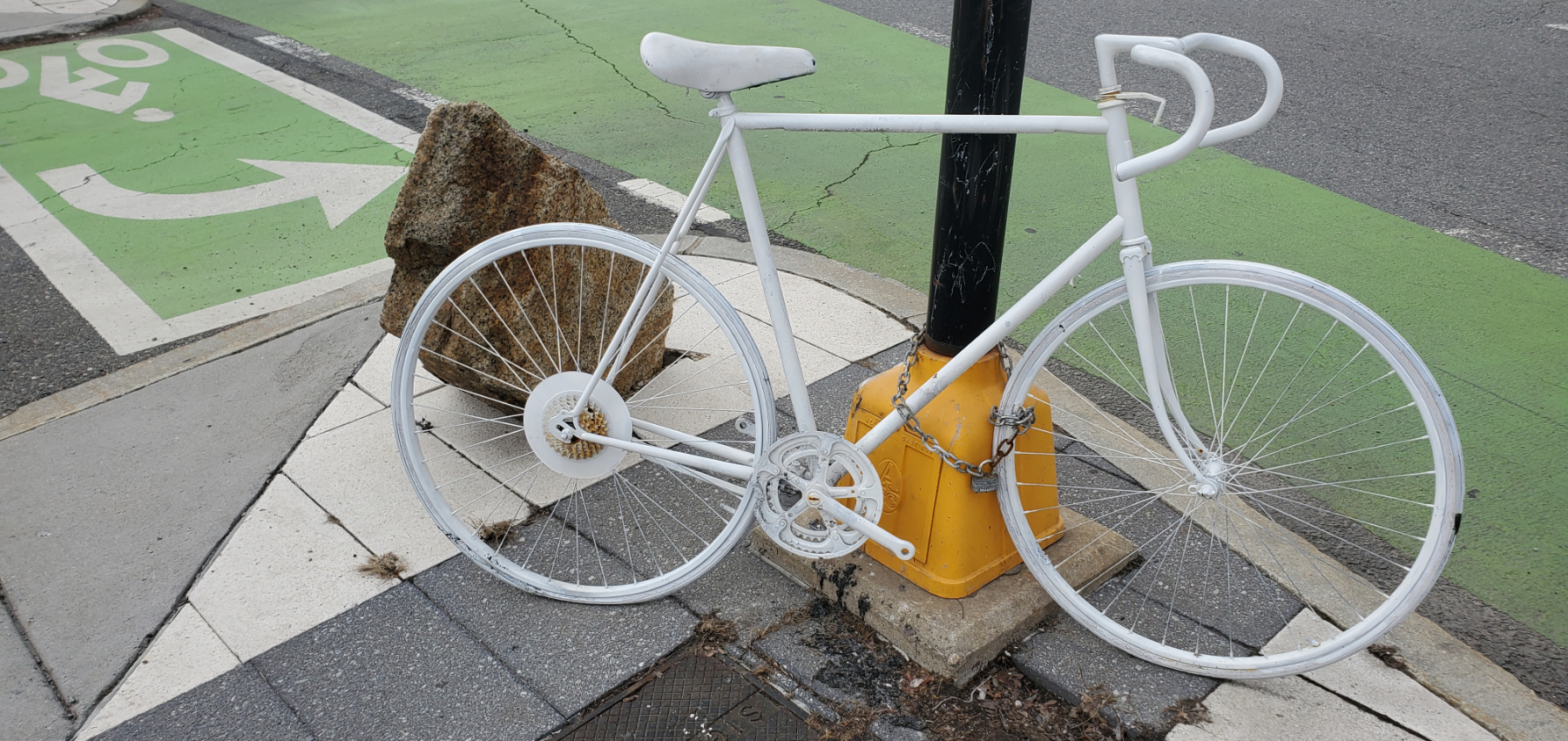 a ten speed bicycle painted white chained to a post
