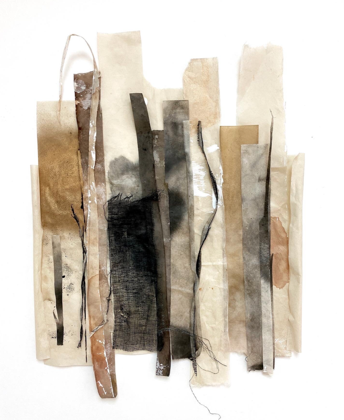 collage of verical papers of varying colors and textures that look like raw and burnt sticks and ribbons