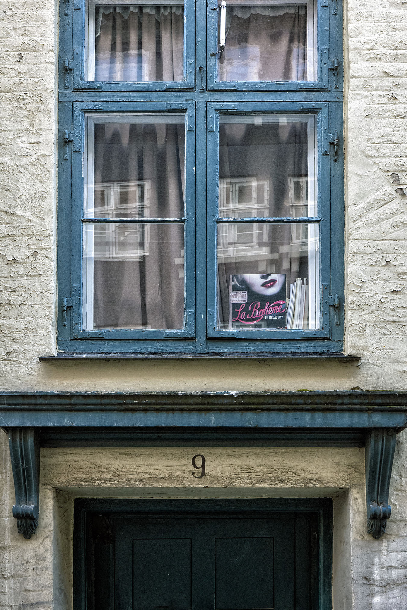 photograph of doorway with number nine on it and above it an outside window with sign for la boheme propped in it