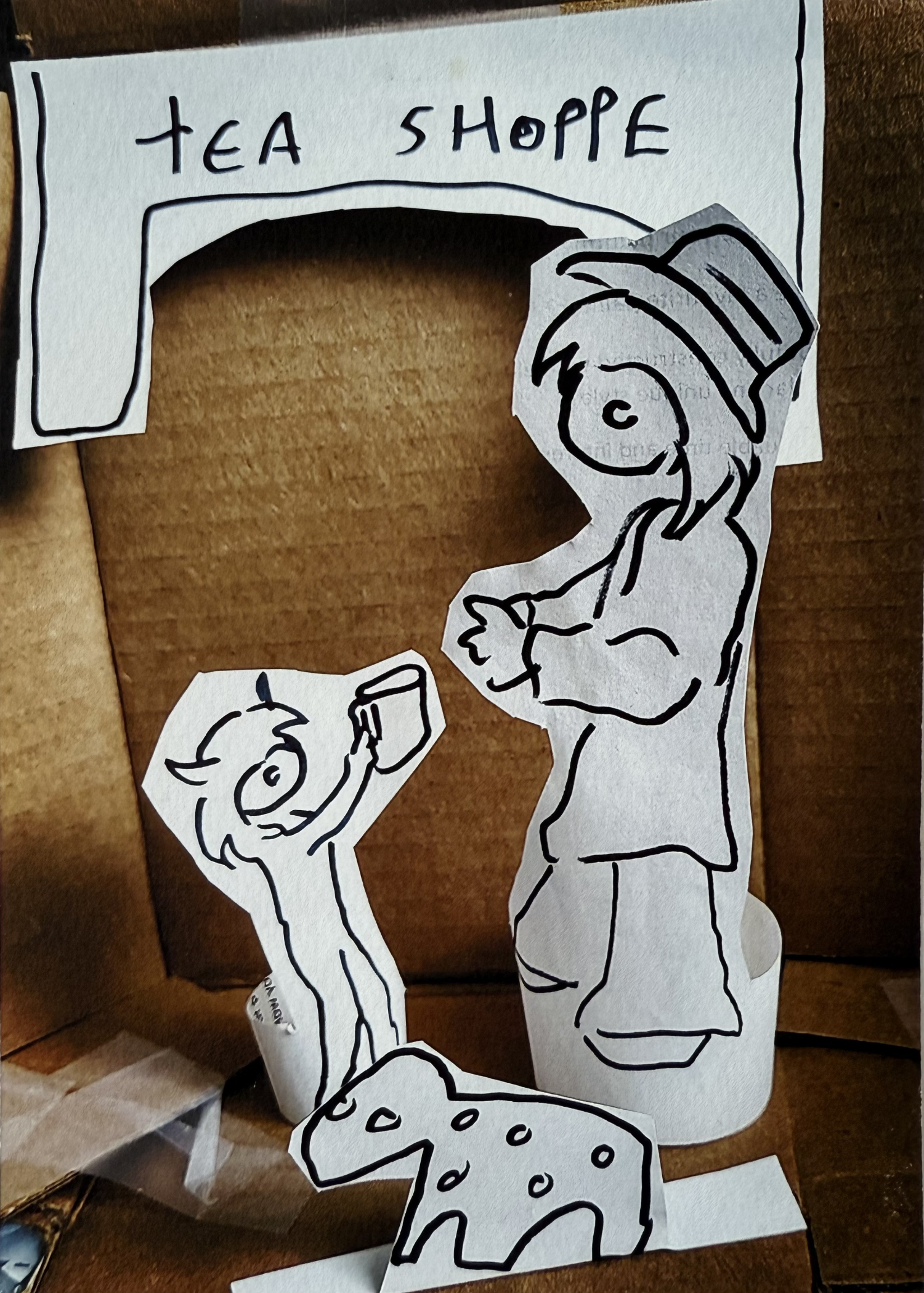 drawings of an adult and a child with a drink and a small animal set up as a diorama inside a corrugated cardboard box